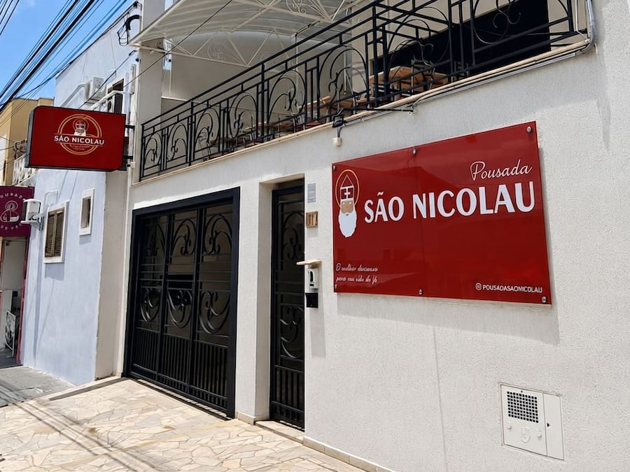 A building with a red sign reading 'SÃO NICOLAU' and a black gate.