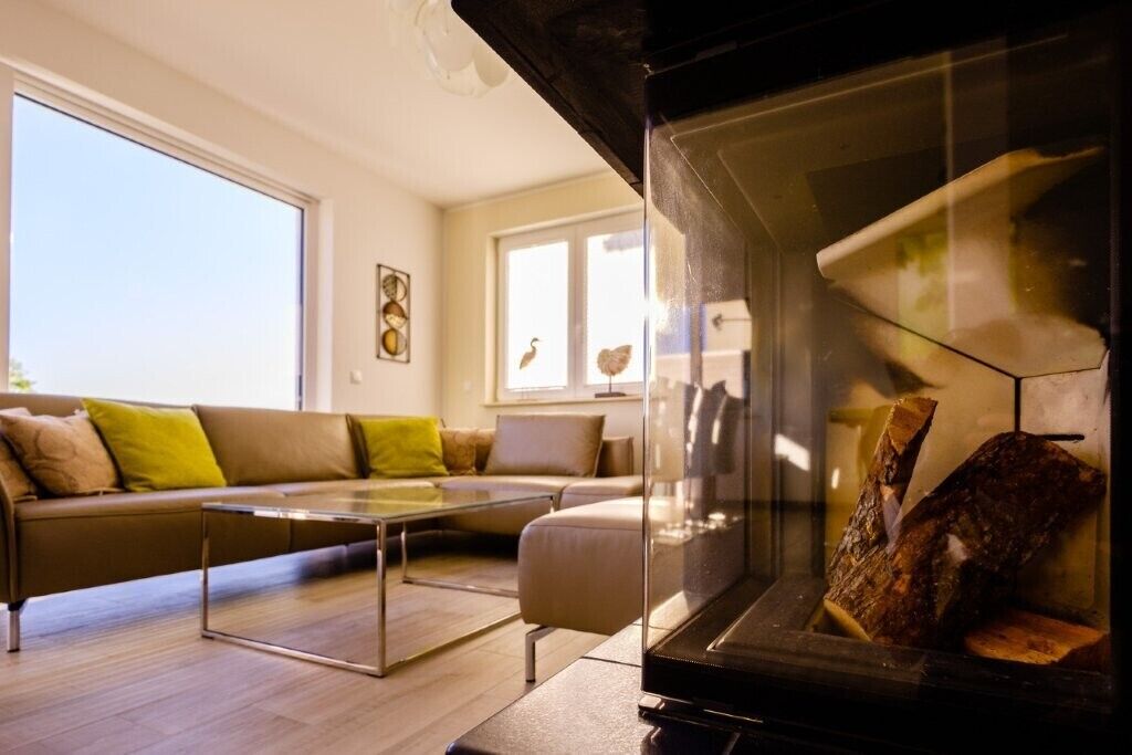 Una sala de estar moderna con una chimenea de vidrio, un sofá de cuero y una mesa de centro de vidrio.