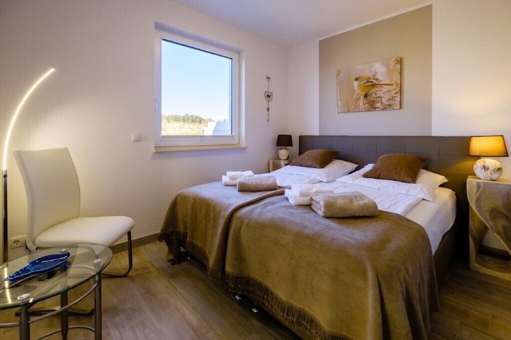 Habitación de hotel con cama, una silla, una mesa, una lámpara y un cuadro en la pared.