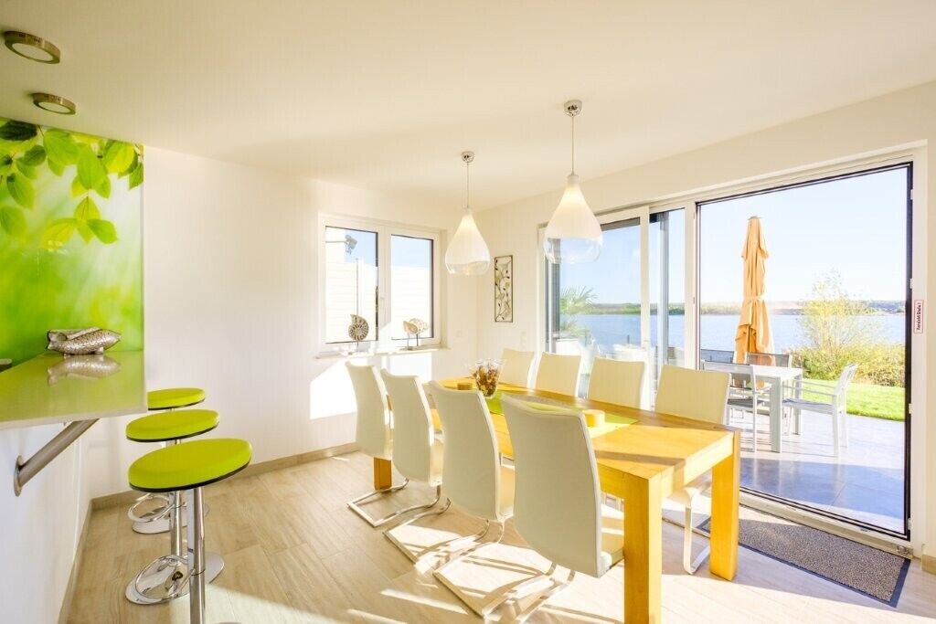 Un comedor con mesa y sillas, vistas al exterior y un ventanal grande.
