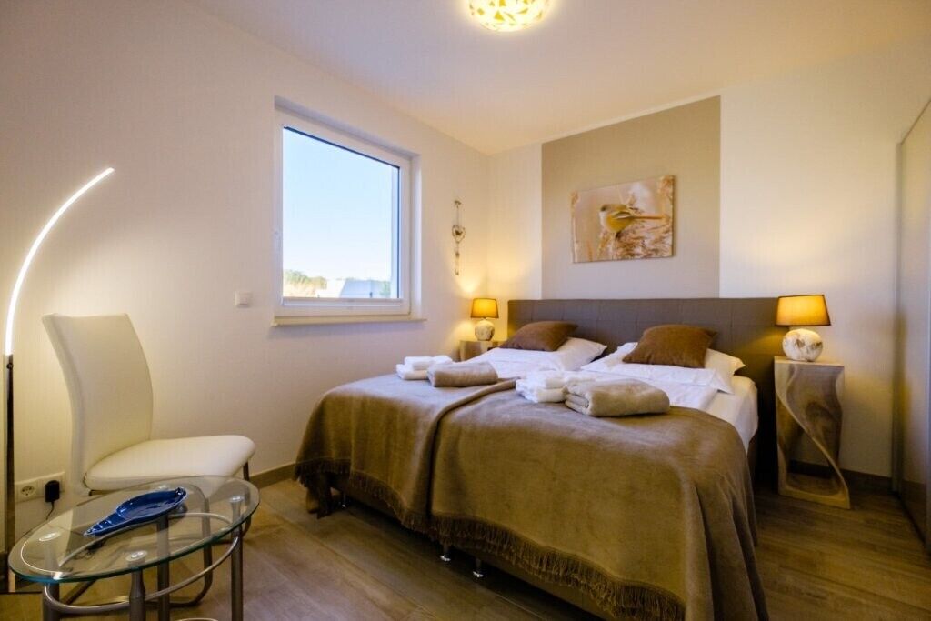 Une chambre d’hôtel avec un lit, deux lampes de chevet, une fenêtre, une chaise et une petite table.