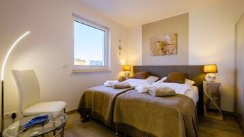 Une chambre d’hôtel avec un lit, deux lampes de chevet, une fenêtre, une chaise et une petite table.