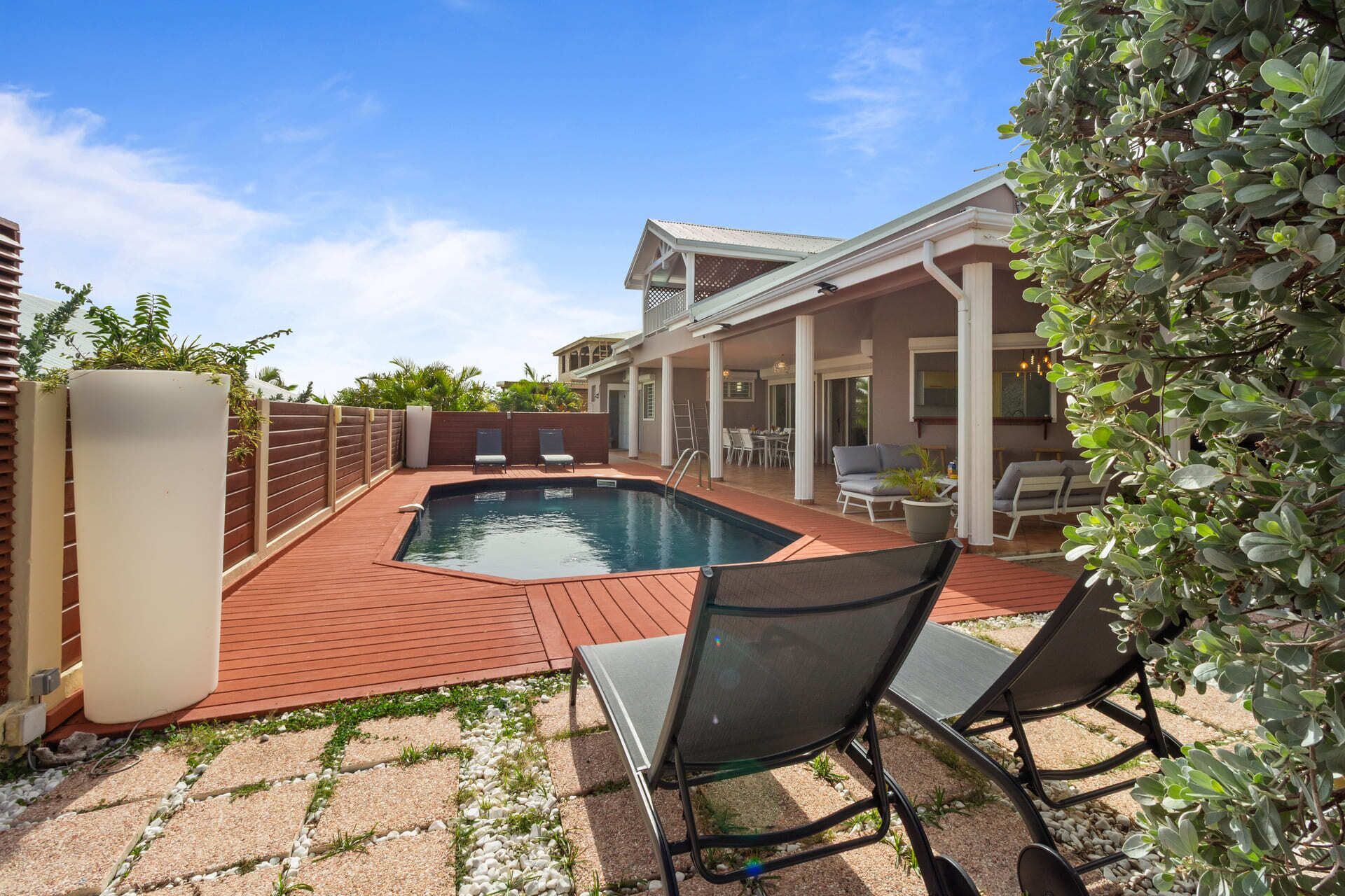 Un jardin avec une piscine, un patio couvert et un espace salon extérieur.