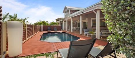 Un jardin avec une piscine, un patio couvert et un espace salon extérieur.