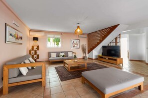 A modern living room with a sofa, a coffee table, a TV stand, and a staircase. - Villa Palmera - Four Bedroom Villa, Sleeps 8 (Saint-François)