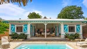 En bygning ved poolen med en overdækket terrasse, udendørs siddepladser og en swimmingpool.