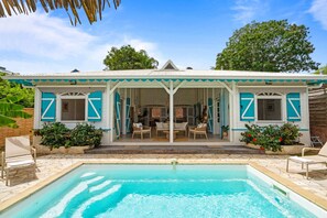 Ein Gebäude am Pool mit einer überdachten Terrasse, Sitzgelegenheiten im Freien und einem Schwimmbecken.
