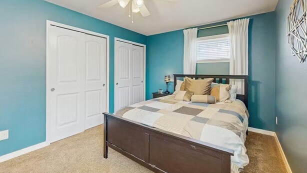Quarto com cama, ventoinha no teto e duas portas.