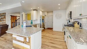 Uma cozinha moderna com armários brancos, bancadas de granito e eletrodomésticos de aço inoxidável.