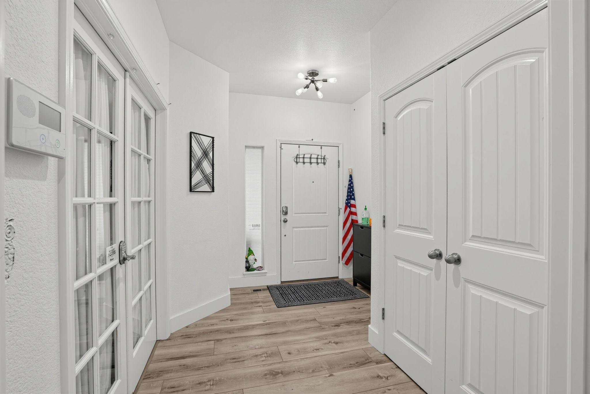 A hallway with white doors, a ceiling fan, and a mat at the entrance.