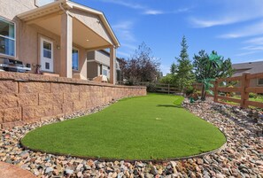 A residential property with a well-maintained lawn, a stone retaining wall, and a wooden fence. - Paw & Peak Lodge: Mini Putt and Wolf Lake Close By (Colorado Springs)