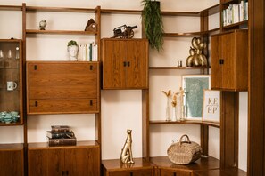 A room with wooden shelving units, books, decorative items, and a framed sign.