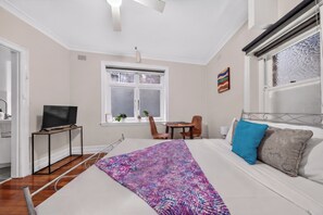 A bedroom with a bed, a TV, a window, a desk, and a chair. - Roslyn Studio Between Harbour Calm and City Energy (Potts Point)