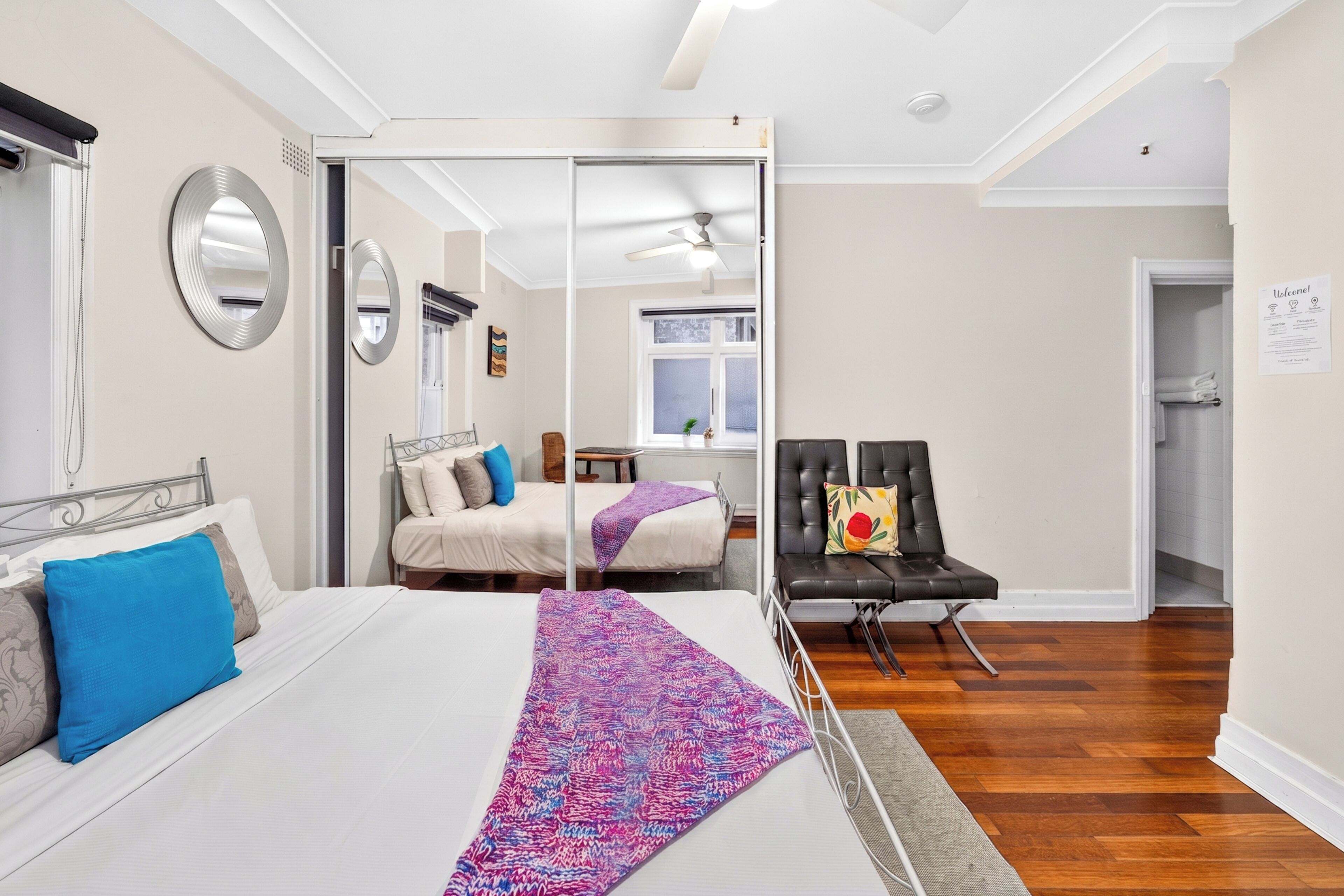 A hotel room with a bed, a chair, a desk, and a mirror.