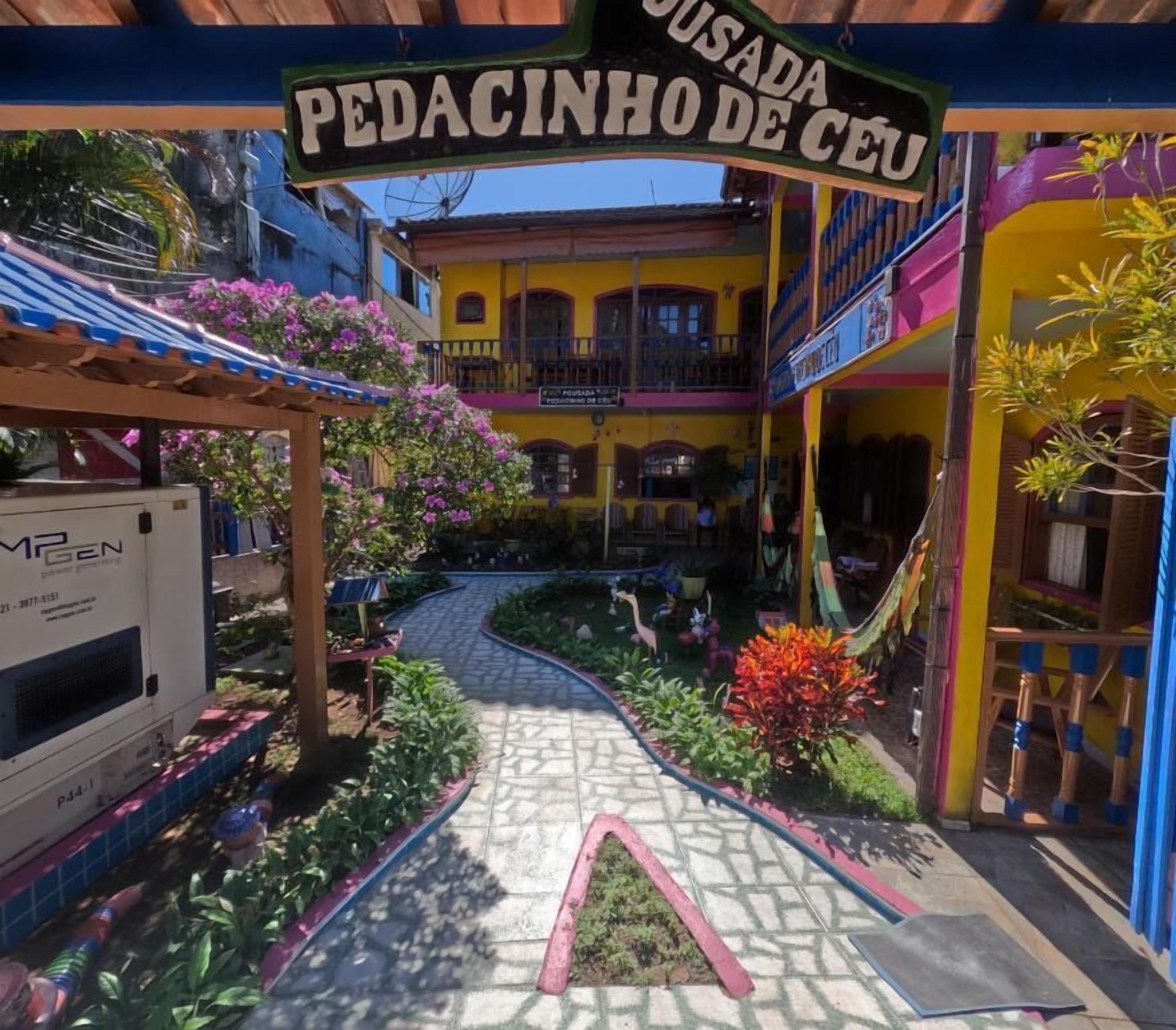 Um pátio colorido com uma placa indicando 'PEDACINHO DE CEU' e uma área de recreação infantil.