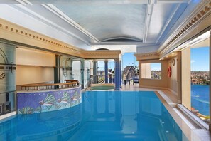 Ein luxuriöser, überdachter Pool mit freiem Blick auf die Stadt durch große Fenster.