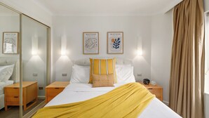 A hotel room with a bed, bedside tables, a mirror, and artwork on the wall. - The Rocks Harbour Escape Resort Living and City View (Sydney)