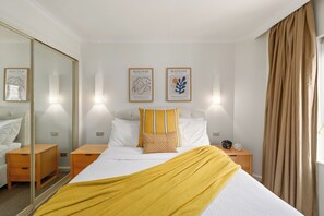 Ein Hotelzimmer mit Bett, Nachttischen, einem Spiegel und Bildern an der Wand.