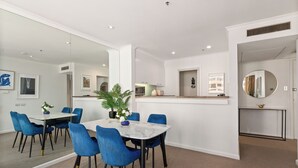 A modern dining area with a marble table, blue chairs, and a potted plant. - The Rocks Harbour Escape Resort Living and City View (Sydney)