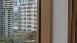 A view through a window with a curtain, featuring tall buildings and a clear sky. - The Rocks Harbour Escape Resort Living and City View (Sydney)