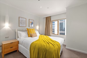 A bedroom with a bed, a nightstand, a window with curtains, and two wall-mounted light fixtures. - The Rocks Harbour Escape Resort Living and City View (Sydney)