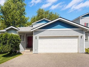 Ein Wohnhaus mit Garage, Eingangstür und kleiner Veranda.