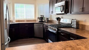 A modern kitchen with dark cabinetry, stainless steel appliances, and a granite countertop. - Unwind at Midtown Haven (Coeur d'Alene)