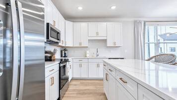 A modern kitchen with white cabinetry, stainless steel appliances, and a large island.