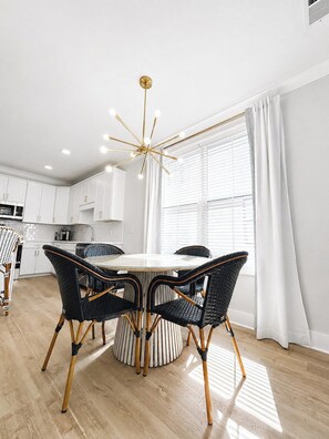 A modern kitchen with white cabinets, a round dining table with black chairs, and a unique star-shaped pendant light. - The Rebel Reserve 3BR+Patio by Velvet Ditch Villas (Oxford)