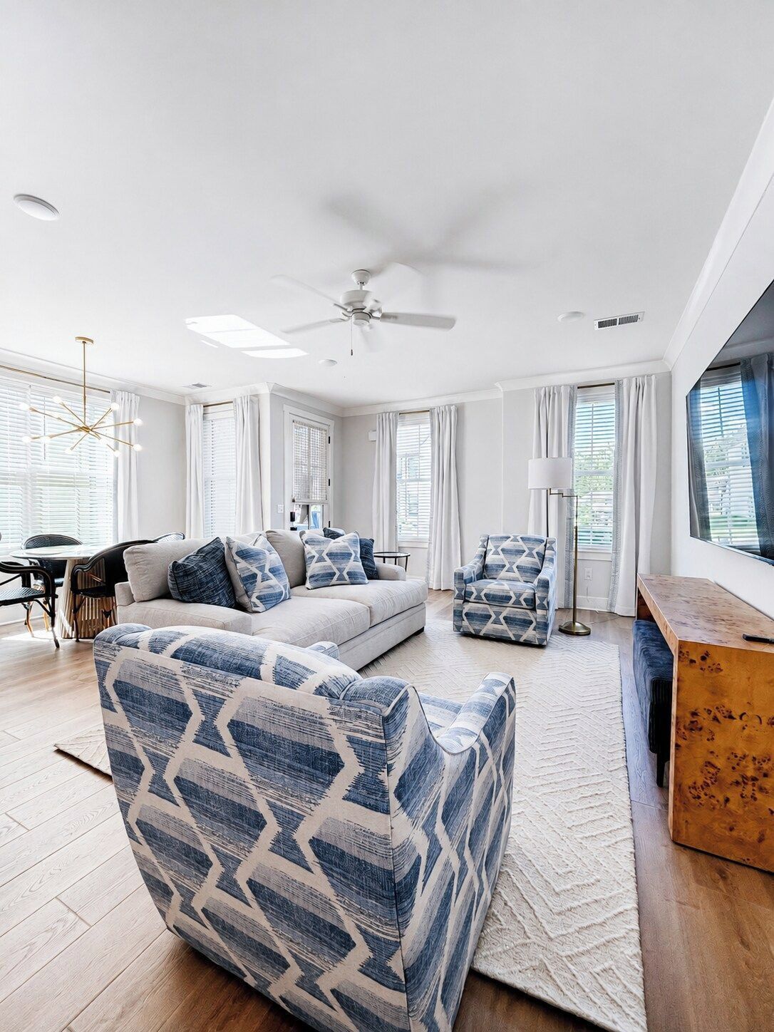 A modern living room with a sofa, armchairs, a coffee table, and a ceiling fan.