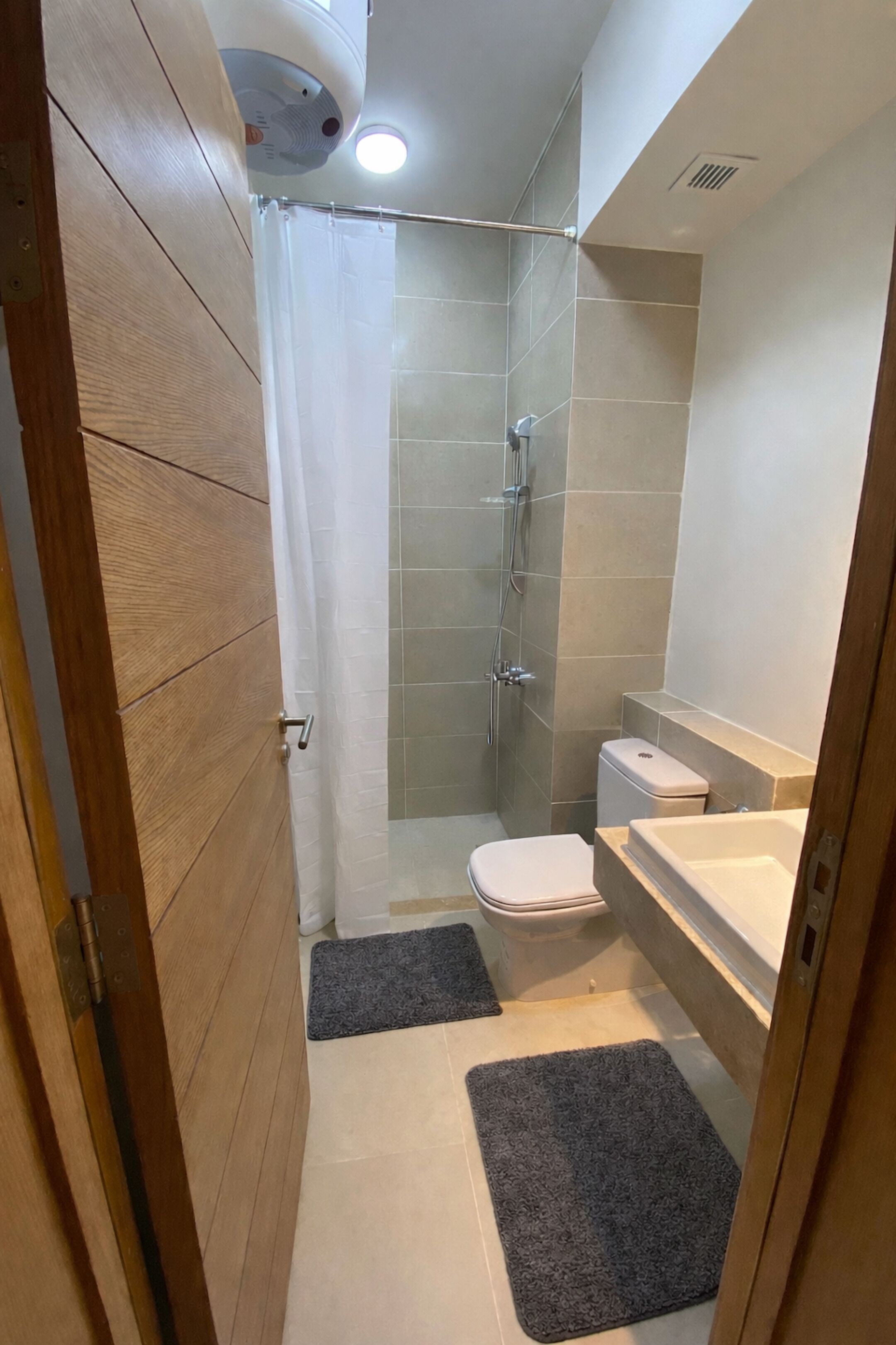 A small, modern bathroom with a shower, toilet, and sink.