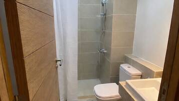 A small, modern bathroom with a shower, toilet, and sink.