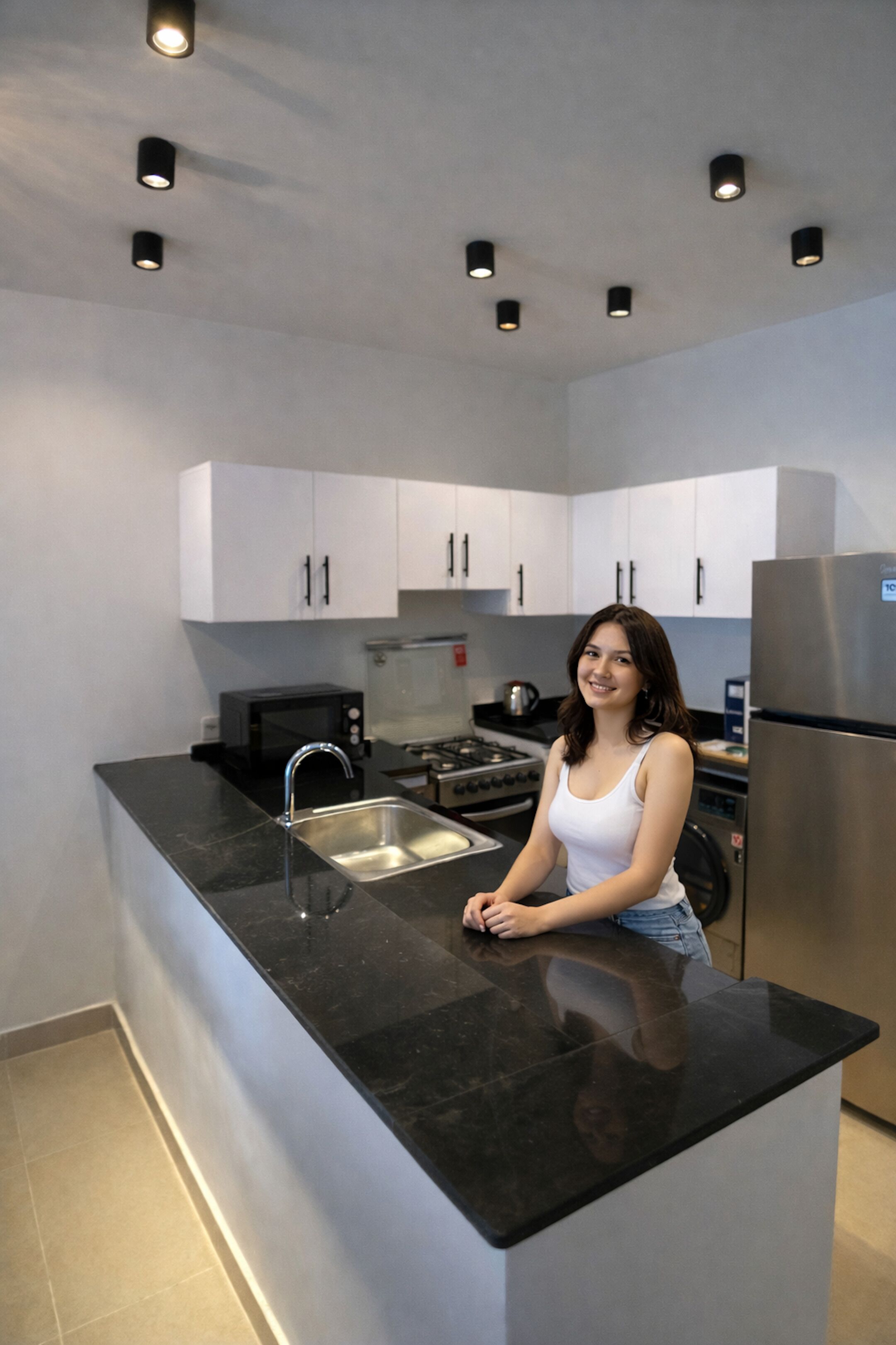 A modern kitchen with white cabinets, a stainless steel sink, and a built-in oven.
