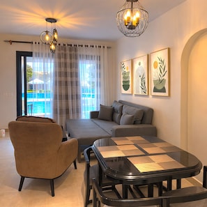 A modern living room with a sofa, armchair, and a glass coffee table.