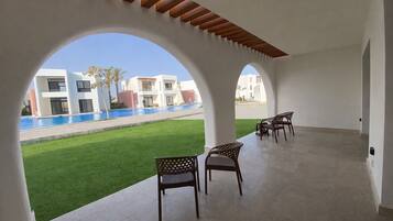 A covered outdoor area with a pool, chairs, and a view of modern buildings.