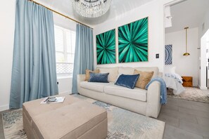 Een moderne woonkamer met een beige bank, blauwe gordijnen en een groot raam.