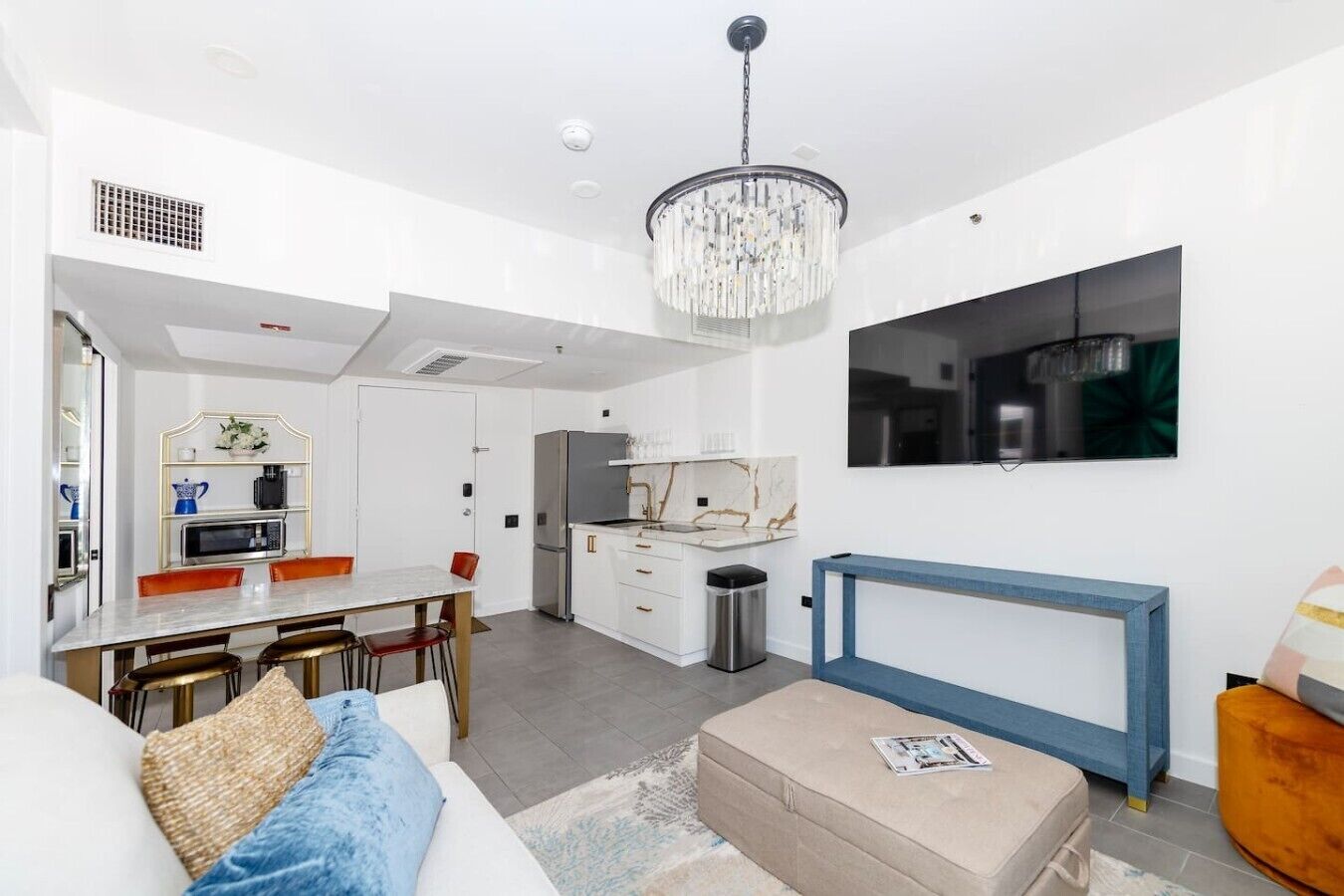 A modern kitchen with a built-in microwave, refrigerator, and a marble backsplash.