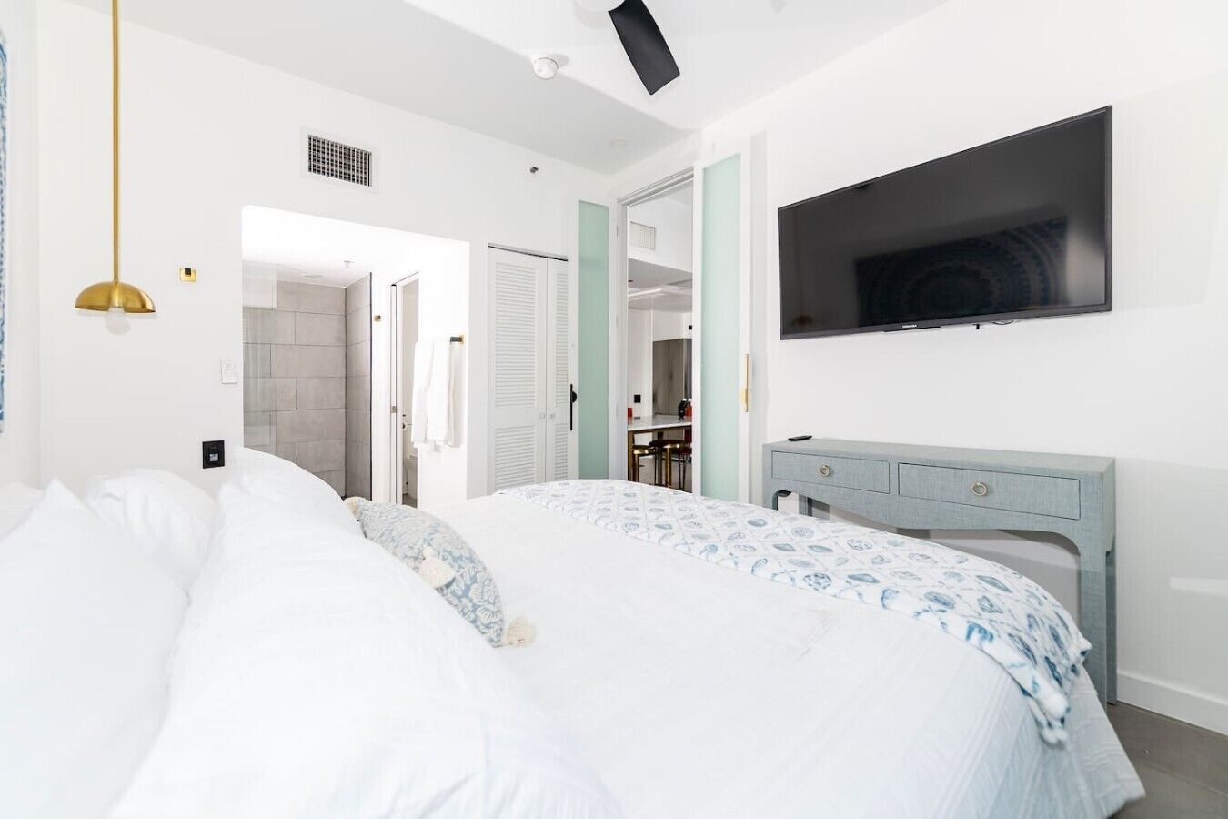 Ein Schlafzimmer mit einem Bett, einem an der Wand befestigten Fernseher und einem Schreibtisch mit Stuhl.