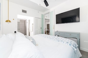 A bedroom with a bed, a TV mounted on the wall, and a desk with a chair. - Stylish Beach Condo in the Heart of South Beach (Miami Beach)