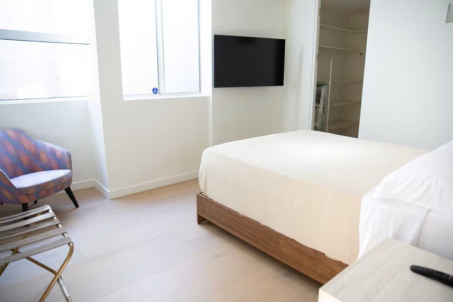 Un dormitorio con cama, una silla, televisor y zona de ducha.