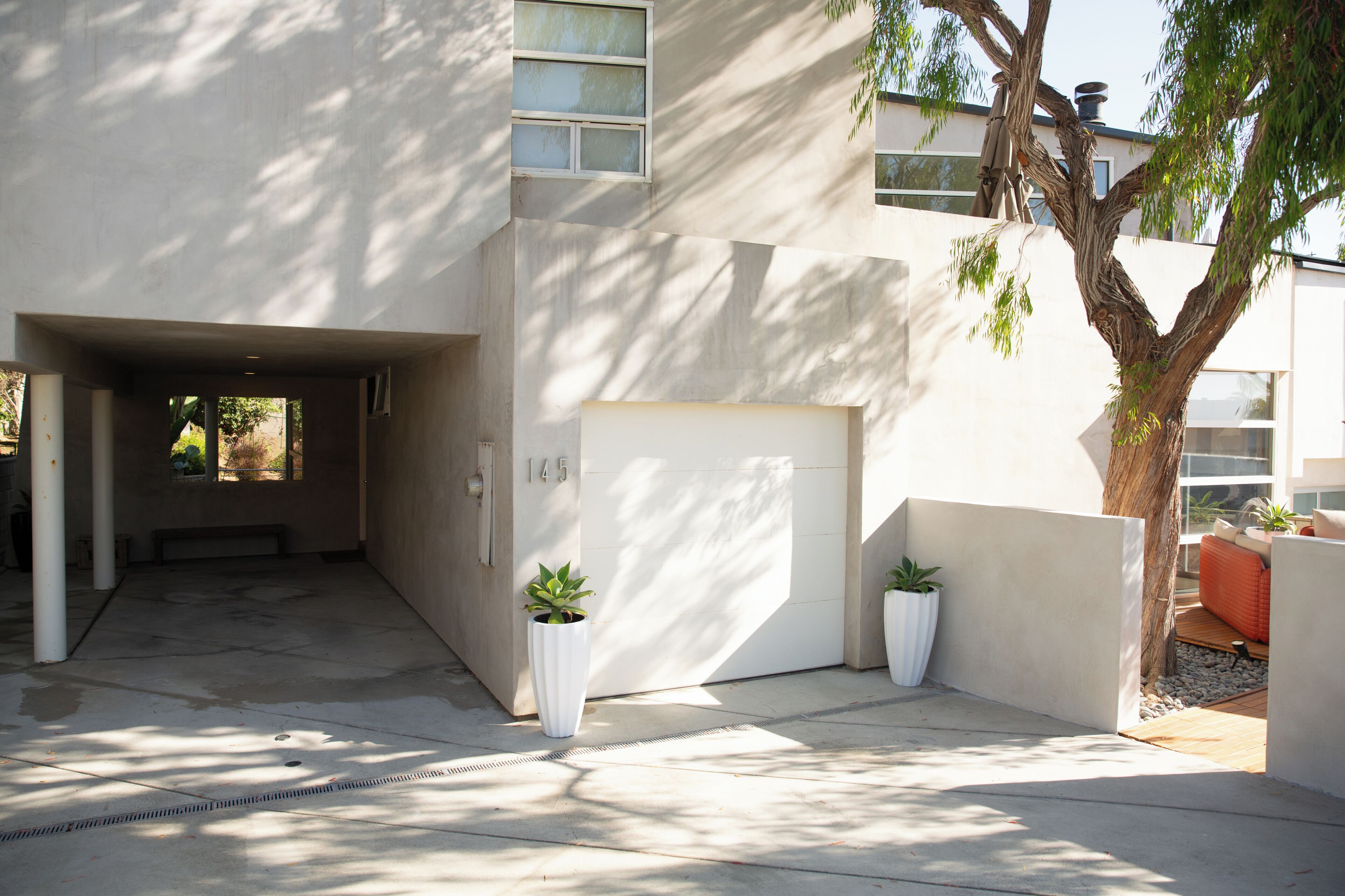 Un edificio moderno con fachada de concreto, puerta de garaje y plantas en macetas.