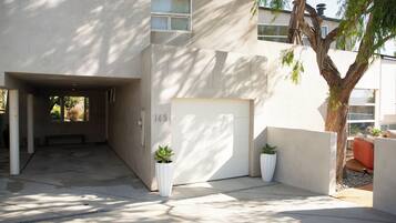 Un edificio moderno con fachada de concreto, puerta de garaje y plantas en macetas.