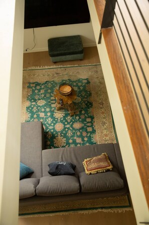 A room with a sofa, a small wooden stool, and a patterned rug.