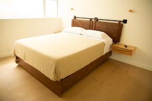 Un dormitorio con cama, mesita de noche y ventana.