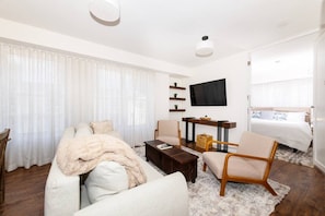 A modern hotel room with a sofa, armchair, coffee table, TV, and a bed. - Newly Renovated Coastal Style Retreat South Beach (Miami Beach)