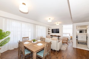 A modern living room with a dining table, sofas, and a TV. - Newly Renovated Coastal Style Retreat South Beach (Miami Beach)