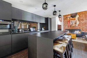 Eine moderne Küche mit einer zentralen Kochinsel, einer Bar und einer Wandmalerei mit Ziegeloptik.