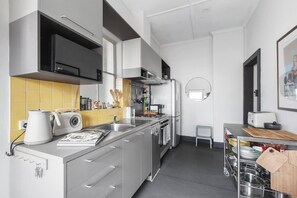 Eine moderne Küche mit Edelstahlgeräten, einer gelb gefliesten Spritzschutzwand und einem kompakten Grundriss.
