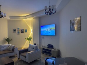 Ein stilvolles Wohnzimmer mit einer Couch, einem Sessel, einem Fernseher und Wanddekoration.