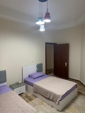 Quarto com cama, mesas de cabeceira, guarda-roupa e luminária suspensa.